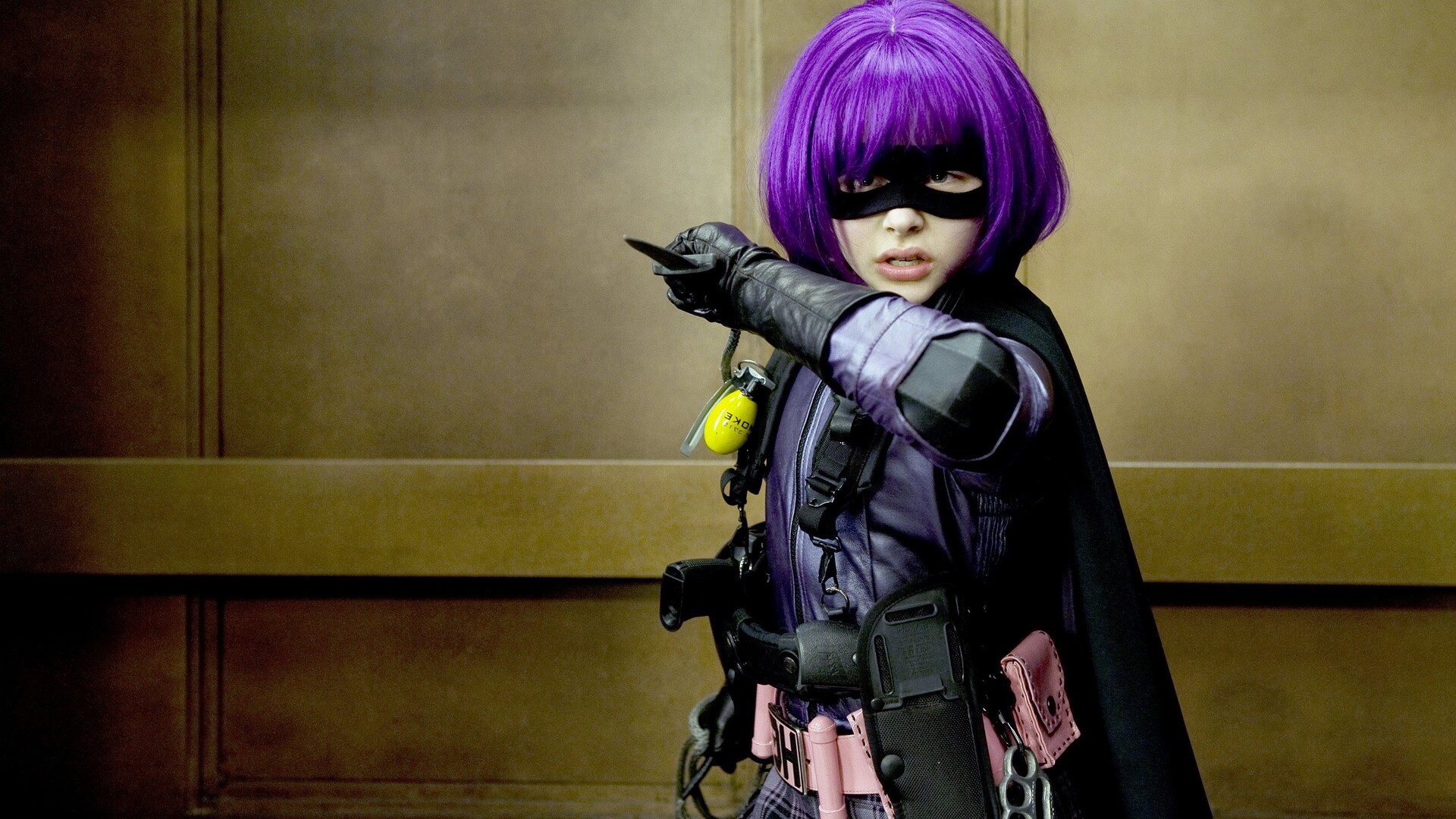 Hit-Girl : le vrai personnage central du film. Un but, des enjeux. On la voit à la sortie d'un ascenseur avec ses armes et sa perruque colorée